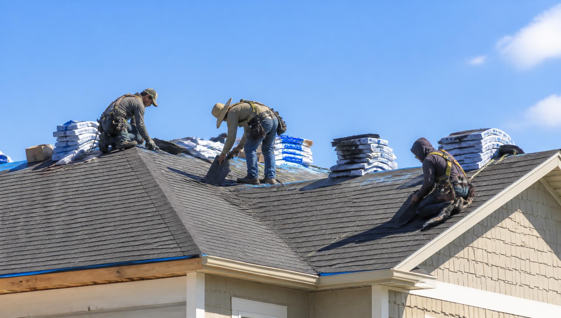 Roofing crew installing shingles on a residential roof